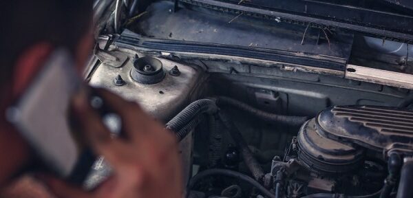 Person on phone whilst checking underneath car hood